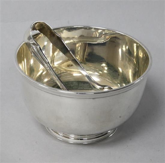 A George V silver sugar bowl and a pair of plated sugar tongs.	